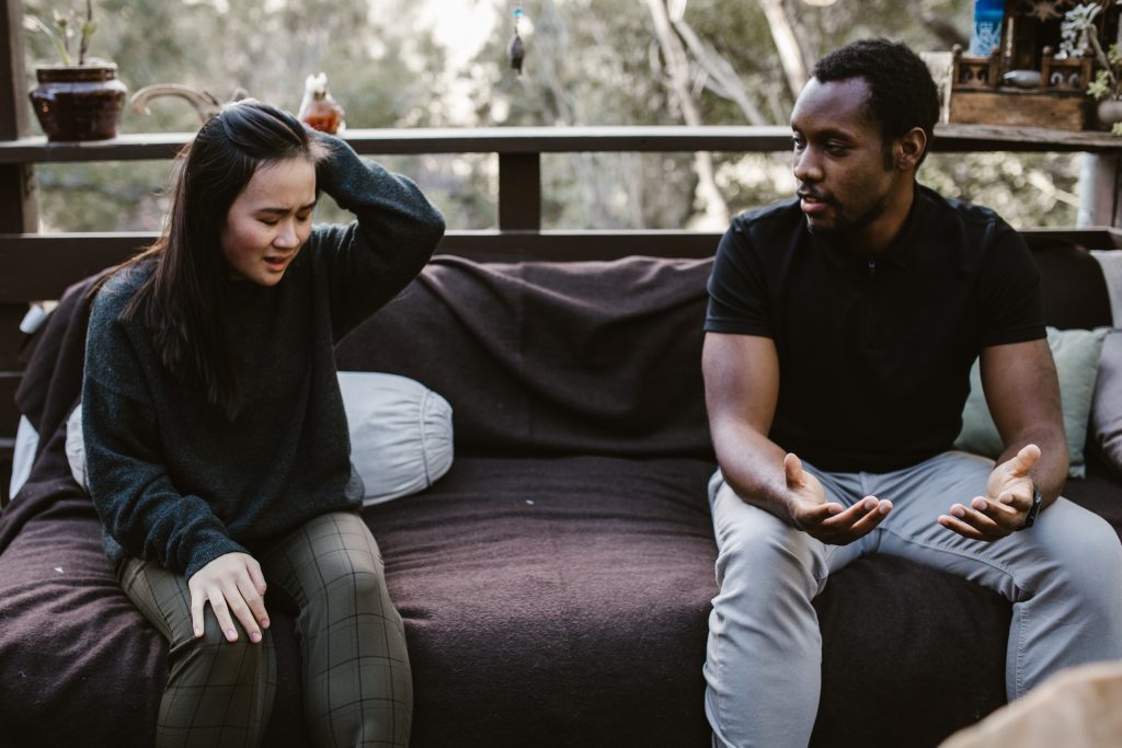 A couple adult camming engaged in conversation while seated on a couch